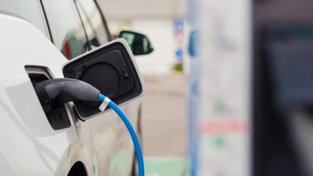 Aurubis_ Nahaufnahme des Netzteils, das an ein Elektroauto angeschlossen ist, das gerade aufgeladen wird.